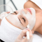 Close up of female face getting healthy clay mask by beautician